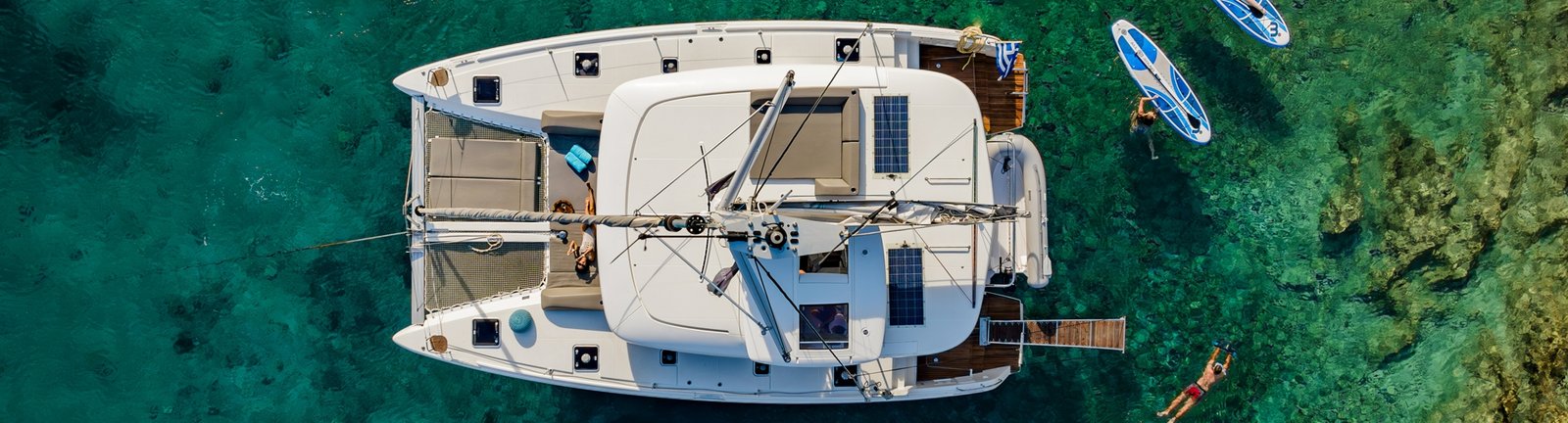 Catamaran sitting in a Greek bay with paddleboards